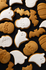 Halloween creepy cookies with sugar icing on black background, top view
