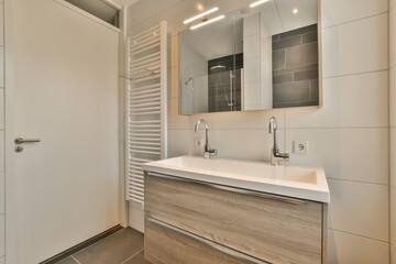 a modern bathroom with white walls and wood flooring, along with a wall mounted mirror above the sink area