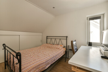 a bedroom with a bed, desk and computer on the floor in front of an open window looking out onto another room