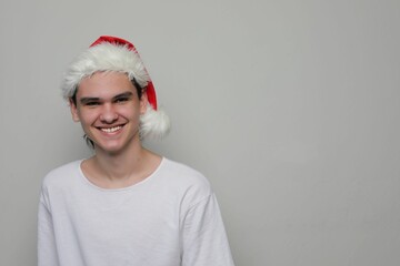 Portrait of a smiling teenager in a Santa Claus hat, white clothes
