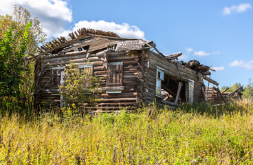 Abandoned destroyed rural wooden house in russian village in summer