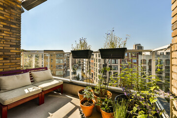 a balcony with potted plants on the windowsills and an outdoor couch in the photo is taken from...