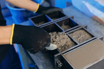Worker making cube concrete casting by steel mould for control quality cement in building lab