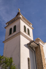 Fototapeta na wymiar Carmelite church bell tower in white color and green garden at the bottom during sunny day