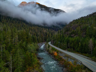 Scenic Highway by Trees and River with Mountains in Background. Colorful Sunrise.