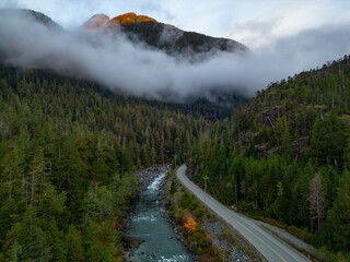 Scenic Highway by Trees and River with Mountains in Background. Colorful Sunrise.