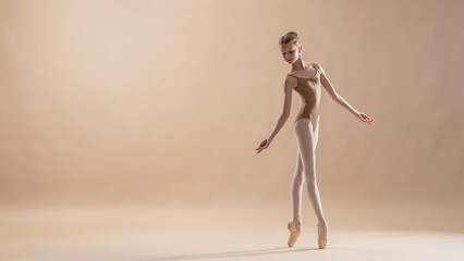 Beautiful young girl professional student ballerina in pointe shoes and a leotard on a light beige background. © Maria Moroz