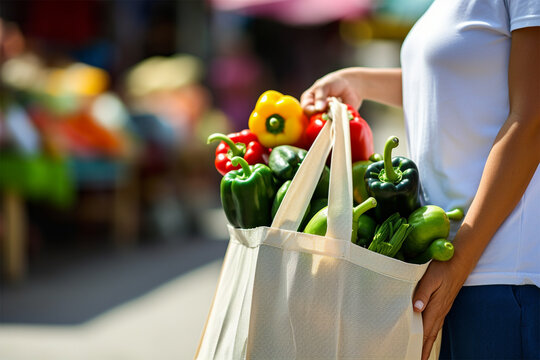 Young woman holding textile glocery eco bag with fruits and vegetables. 