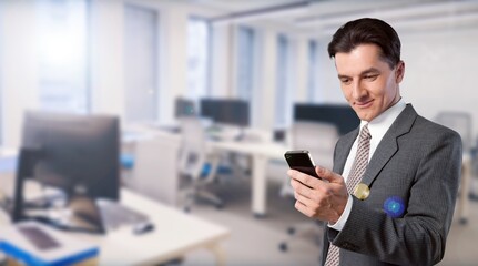 Smiling young businessman work on smartphone in office.