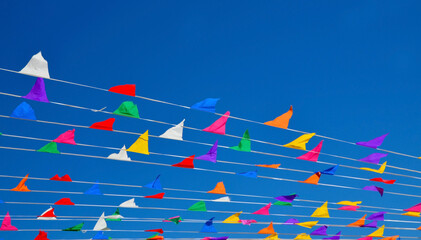 Multicolored triangular small flags to celebration party against blue sky.Street holiday concept for design.Selective focus.
