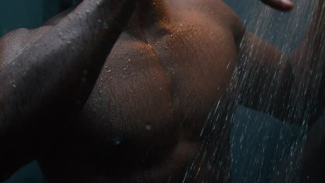 African American bare wet man dancing in shower listen music ethnic naked sexy muscular athletic guy singing song funny dance move in dark bathroom male morning hygiene washing body hot falling water