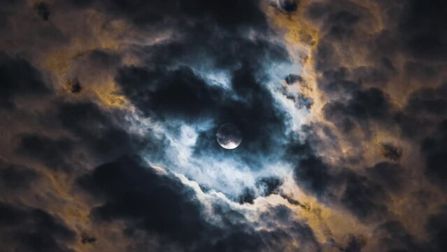 The mesmerising beauty of the night sky. Full moon time lapse. Clouds look like smoke from a fire. Black and yellow colours. Mysticism and terror
