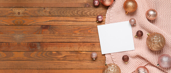 Beautiful Christmas composition with blank card, plaid and balls on wooden background with space...