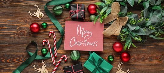 Greeting card with text MERRY CHRISTMAS, gift boxes and decor on wooden background