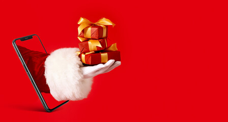 Hand of Santa Claus with gifts on color background