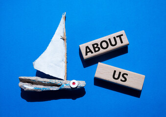 About us symbol. Concept word About us on wooden blocks. Beautiful blue background with boat....