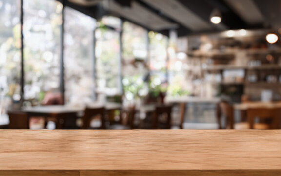 Photo of empty wooden table, where you can add your cup of coffee or some decoration. Focus on the table and blur on the background. 