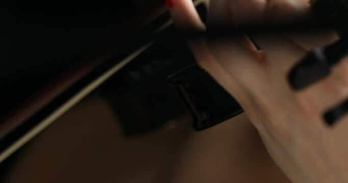 Front view of a young woman playing a black electric violin ( focus changes)
