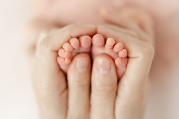 Feet of a newborn baby in the mother's arms. legs of a newborn baby in his hands. baby's legs. baby feet on background