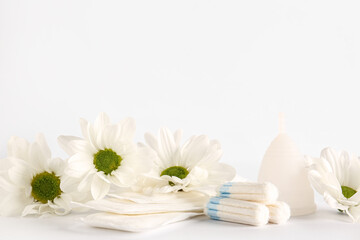 Obraz na płótnie Canvas Female hygiene items and chamomile flowers on light background