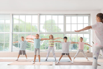 Fototapeta na wymiar Group of little children practicing yoga with instructor in gym
