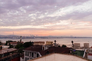Beautiful landscape with sunrise over the city roofs, the bay and the city in the background. Dawn from the roofs of Istanbul overlooking the Bosphorus. Istanbul, Türkiye - October 16, 2023