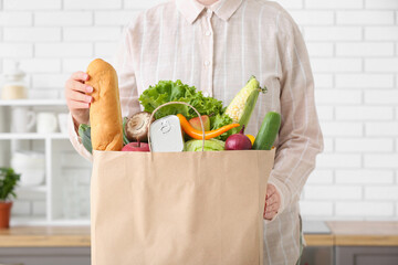 Woman and paper bag with different products in kitchen