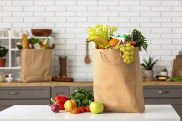 Shopping paper bag with fresh products on table in kitchen