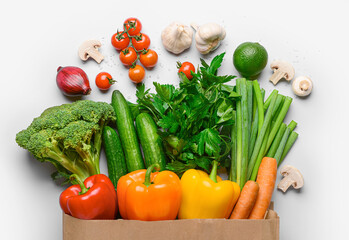 Paper bag with fresh vegetables, fruits and mushrooms on white background
