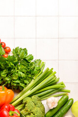 Fresh vegetables and greenery on white tile background