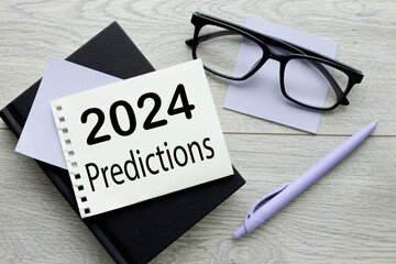 2024 predictions torn paper on a wooden table. black notepad. words