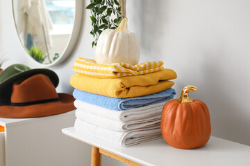 Stack of clean towels and decor on table near light wall
