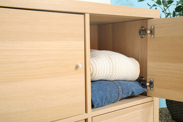 Fototapeta na wymiar Warm clothes in wooden wardrobe, closeup