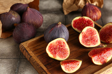 Wooden board with fresh ripe figs on grey tile table