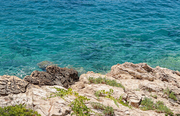Fototapeta na wymiar Rocky shore and turquoise calm sea water on sunny summer day