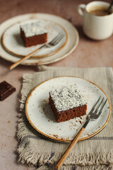 Easy chocolate and coconut cake. Rustic napkin and brown background. Cup of coffee.