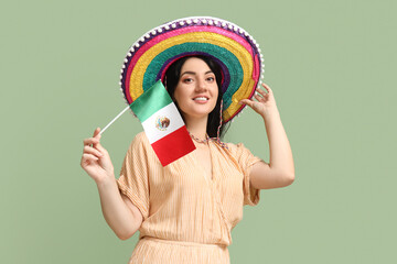 Beautiful Mexican woman in sombrero and with flag on green background