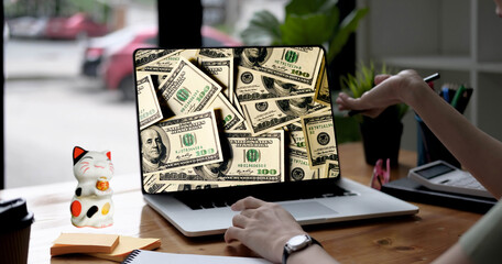 Mujer de negocios exitosa observando en su laptop los dólares que está ganando. Mientras toma su café y tiene a su gatito de la suerte sobre su escritorio. - obrazy, fototapety, plakaty