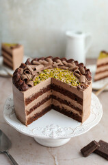 Chocolate cake decorated with chocolate ganache cream and chopped pistachios.