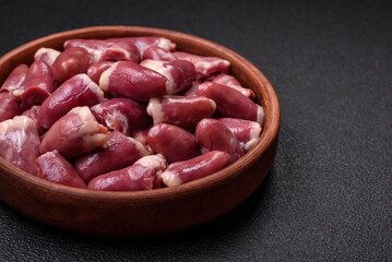 Fresh raw chicken, turkey or duck hearts on a ceramic plate with salt and spices