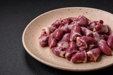 Fresh raw chicken, turkey or duck hearts on a ceramic plate with salt and spices