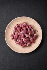 Fresh raw chicken, turkey or duck hearts on a ceramic plate with salt and spices