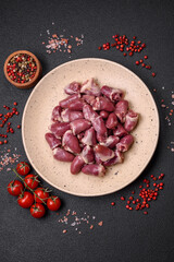 Fresh raw chicken, turkey or duck hearts on a ceramic plate with salt and spices