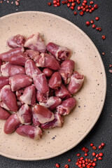 Fresh raw chicken, turkey or duck hearts on a ceramic plate with salt and spices