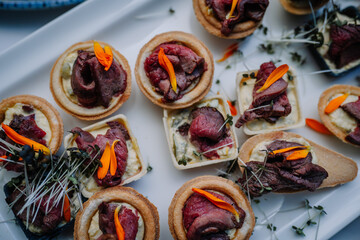 Elevate your party with gourmet beef snacks like mini sliders, beef crostini. Close up, soft focus.