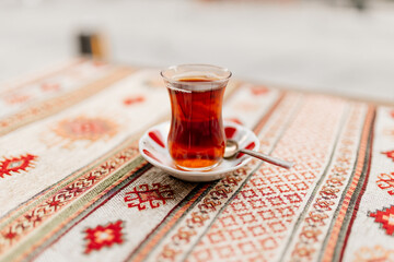 Turkish black tea in national dishes stands on the table with a napkin with Turkish patterns. Dessert close-up. Breakfast in a cafe. Turkish ornament - obrazy, fototapety, plakaty