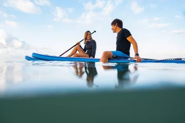 Foto op Canvas Young man and woman on the sea with a paddle surf board © Philippe