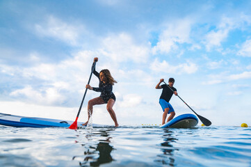 Woman competing with man in paddleboard in the mediterranean sea