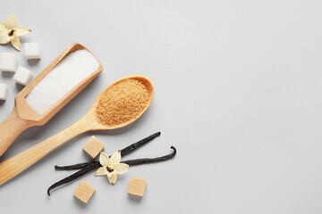 Fototapeta na wymiar Wooden scoop and spoon with aromatic vanilla sugar on grey background
