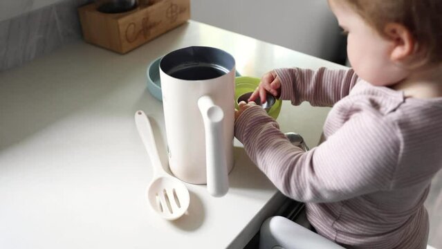 Toddler playing in the kitchen with household objects